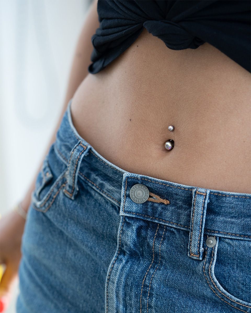 Navlepiercing av titan med to stener
