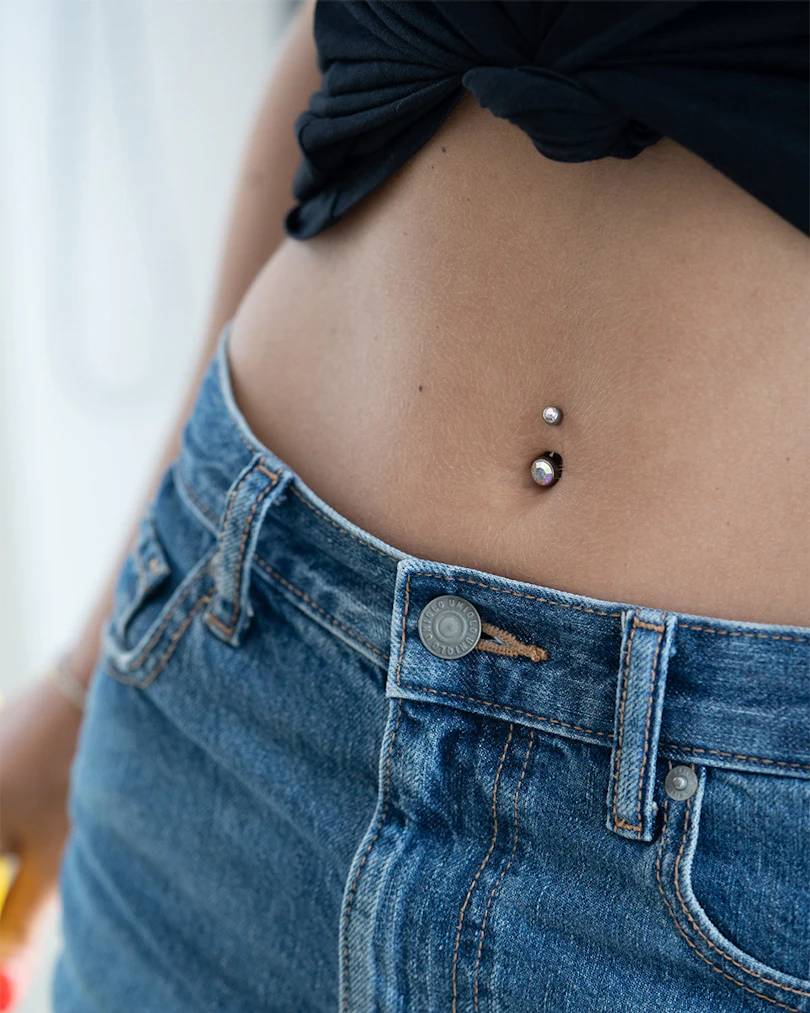 Navlepiercing av titan med to stener